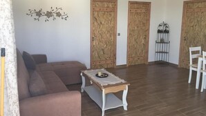 A living room with a brown sofa, a small table with a plate, and two wooden doors.