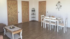 A spacious room with a wooden ceiling, a dining table with chairs, and three wooden doors.