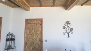 A room with a wooden ceiling, a wooden door, a metal wall decoration, and a metal shelf with a decorative item.