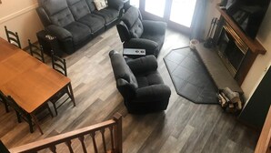 Una sala de estar con un sofá oscuro, una mesa de comedor de madera y una chimenea.