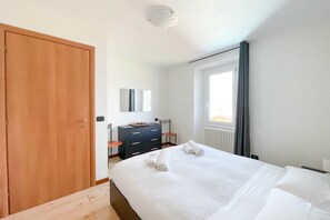 Ein Schlafzimmer mit einem großen Bett, einem Holzschrank, einer Kommode und einem Fenster mit Vorhängen.