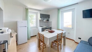 A compact kitchen with a dining table, chairs, a refrigerator, a stove, and a sink. - BLUE HOUSE 3 by Design Studio (Bellano)