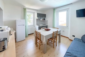 Cocina compacta con una mesa de comedor, sillas, un refrigerador, estufa y lavamanos.