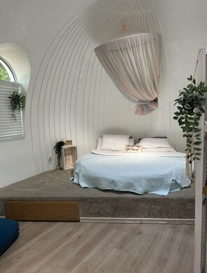 A bedroom with a curved ceiling, a bed with white bedding, a small bedside table, and a window with blinds. - ❌not a tent❌ Unique DOME 💜Blue Moon 💜 (Largo)