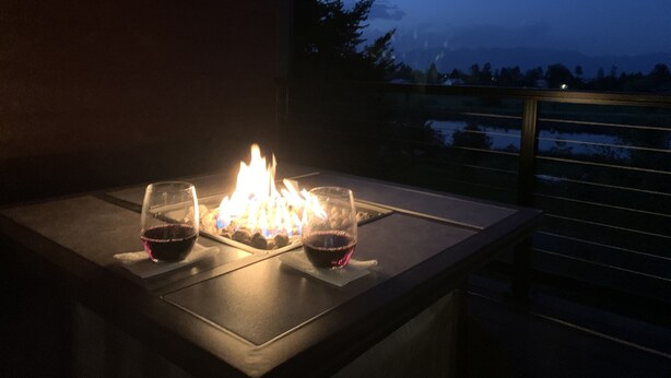 A table with a lit fire and two glasses of red wine. - Swan View Refuge-Luxury 2 bedroom sleeps 4 (Somers)
