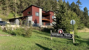 A two-story building with a red exterior, surrounded by a forested area. - Swan View Refuge-Luxury 2 bedroom sleeps 4 (Somers)
