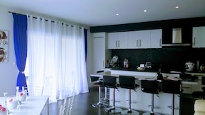 Uma cozinha moderna com armários brancos, bancada preta e três banquetas.