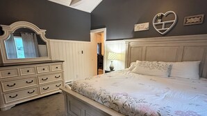 A bedroom with a bed, dresser, mirror, and wall decorations.