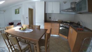A compact kitchen with a dining table, chairs, a stove, and cabinets. - Villetta Gina (Avola)