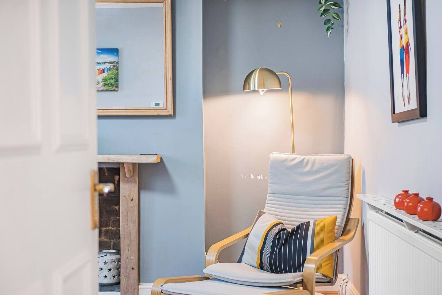 A cozy room with a wooden chair, a floor lamp, and a fireplace.