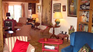 Ein gemütliches Wohnzimmer mit gestreifter Möblierung, einem Fernseher, einem Bücherregal und einem Gemälde.