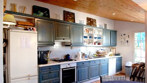 Eine Küche mit blauen Schränken, einem weißen Kühlschrank und einem Essbereich mit blauem Tisch und Stühlen.