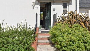 A white building with a front door, a small porch, and a brick pathway leading to the entrance. - 3 bedroom accommodation in Bampton, near Tiverton (Bampton, near Tiverton)