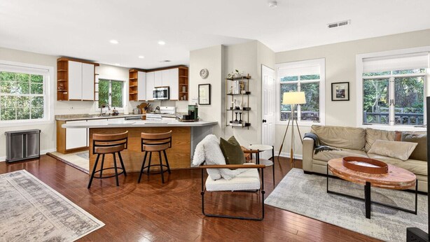 A modern kitchen with a central island, bar stools, a sofa, and a coffee table. - Stylish Inman Park Condo, Walk to Beltline (Atlanta)