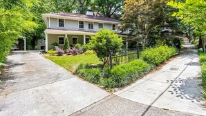 A two-story house with a front porch, surrounded by a well-maintained garden and a sidewalk. - Stylish Inman Park Condo, Walk to Beltline (Atlanta)