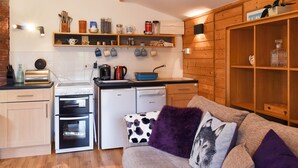 A compact kitchen with modern appliances, wooden shelves, and a cozy seating area.