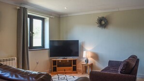 Una sala de estar con una televisión de pantalla plana, una lámpara, un sofá y una mesita.