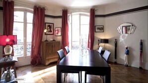 Ein Esszimmer mit einem langen Tisch, roten Vorhängen und einem Holzschrank.