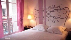 Ein Schlafzimmer mit Bett, Nachttisch, Lampe und einer Wanddekoration.