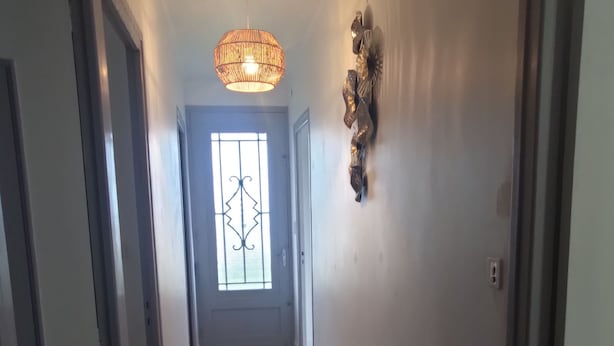 A hallway with a door at the end, a decorative wall piece, and a textured rug on the floor. - Mountain spirit, adventure on your doorstep (BARLEST)