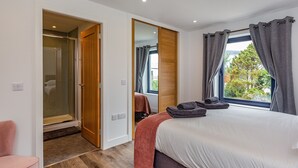 Ein Schlafzimmer mit Bett, Stuhl, Spiegel und einem Fenster mit Vorhängen.