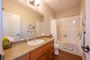 A bathroom with a sink, mirror, and a shower area. - Sept Long Weekend | Sleeps 8 | Close to Pool | Private Beach (Osoyoos)