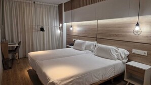 Una habitación de hotel moderna con una cama grande, mesitas de noche, un escritorio y una silla.