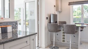 A modern kitchen with a large window, a dining area with bar stools, and a television.