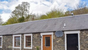 A stone building with a grey tiled roof, a wooden door, and a satellite dish. - 1 bedroom accommodation in Walkerburn, near Peebles (Walkerburn, near Peebles)