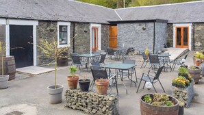 A courtyard with stone buildings, outdoor seating, and potted plants. - 1 bedroom accommodation in Walkerburn, near Peebles (Walkerburn, near Peebles)