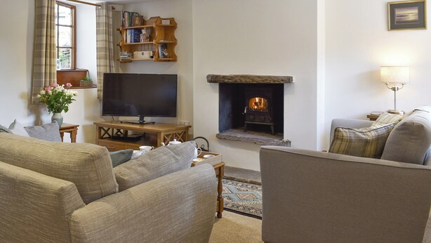 A cozy living room with a fireplace, a television, and comfortable seating. - The Old Candle House (Longnor, near Buxton)