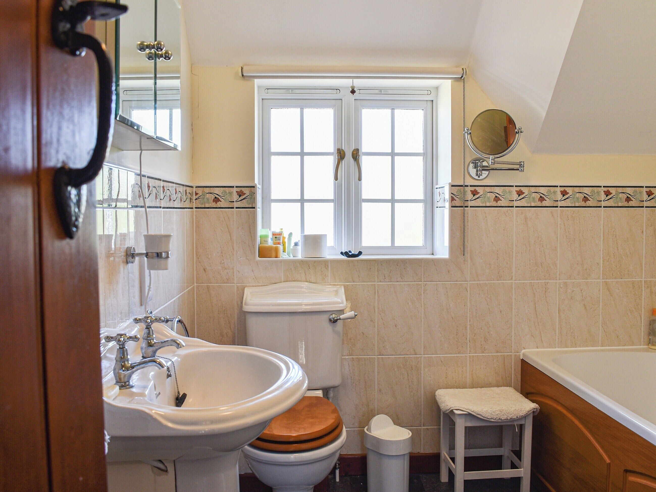 A bathroom with a sink, toilet, and window.