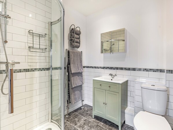 A bathroom with a glass shower enclosure, a sink with a cabinet, and a toilet.