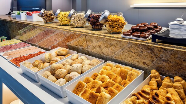 Een buffet met diverse gerechten, waaronder gebak, belegde broodjes en salades.