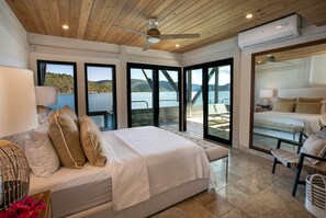 A bedroom with a bed, a ceiling fan, and a view of the lake.