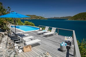 A wooden deck with lounge chairs, a pool, and a view of the sea. - The Cliff House at Steele Point (West End)