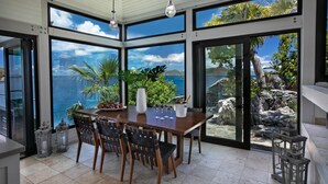 Un área de comedor con vista al océano, una mesa con sillas y una planta en maceta.