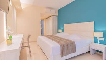 Una habitación de hotel moderna con una cama grande, un escritorio con una silla, una mesita de noche pequeña y un televisor.