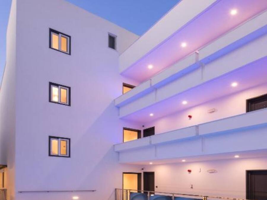 A modern hotel with a swimming pool, multiple balconies, and a clean, white facade.
