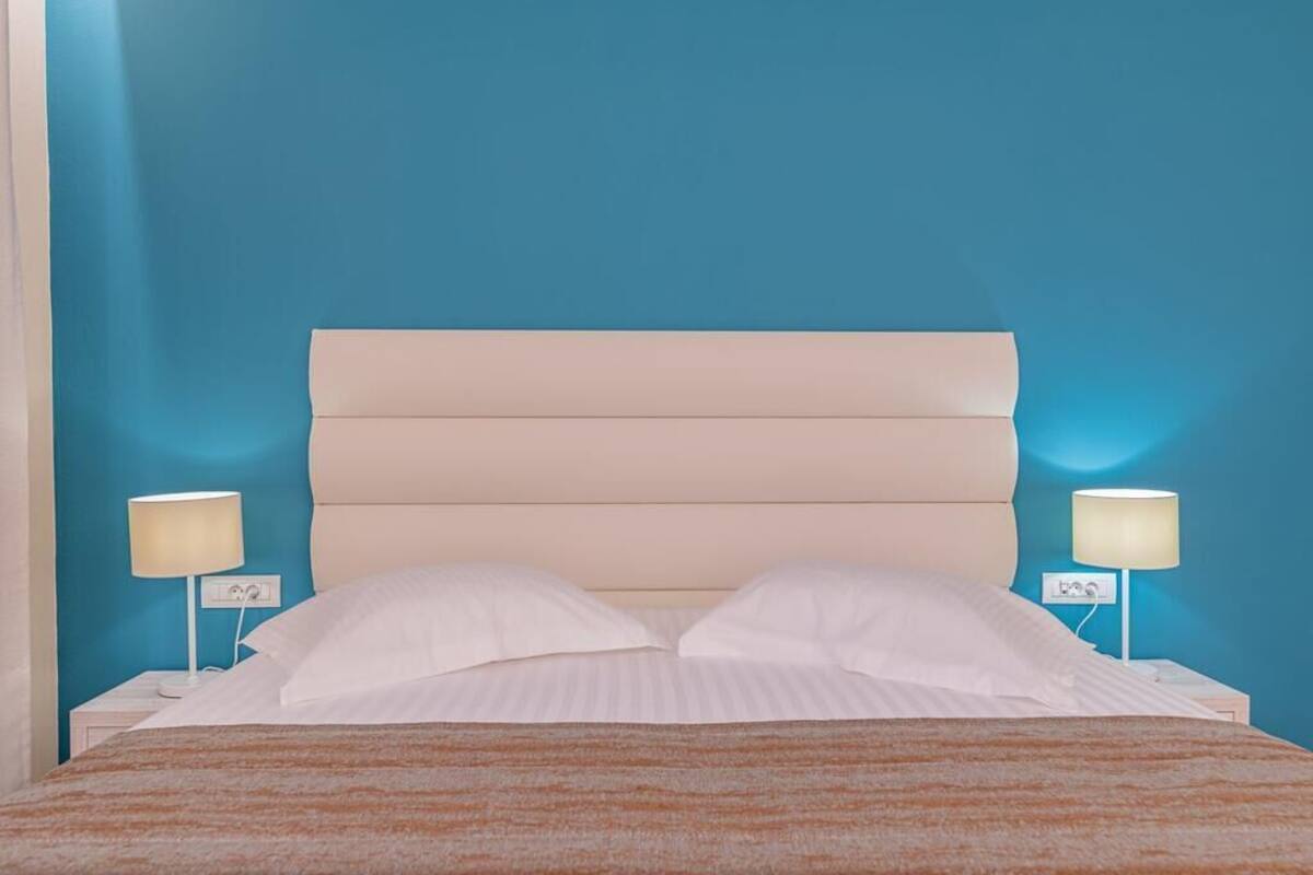 A bed with a headboard, two bedside lamps, and a striped blanket.