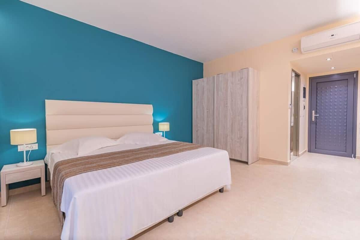 A bedroom with a bed, bedside tables, a wardrobe, and a door.