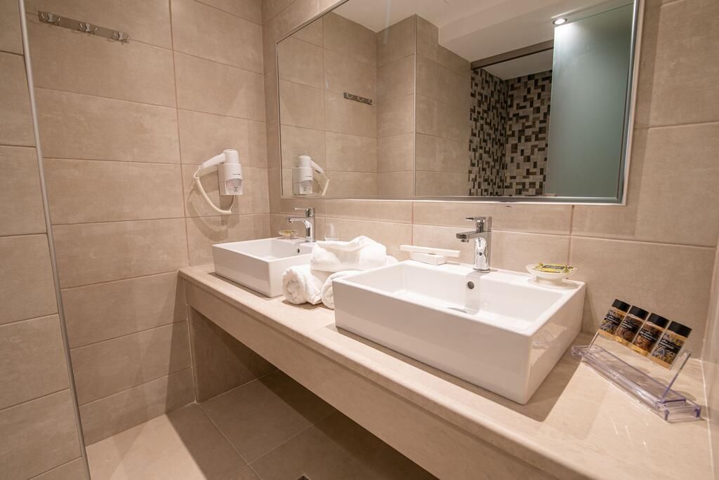 Un baño moderno con dos lavamanos, un espejo grande y una zona de ducha.
