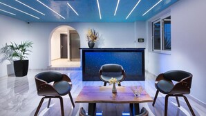 A modern interior with a starry projection on the wall, two chairs, a table, and a potted plant. - Christa (Kos)