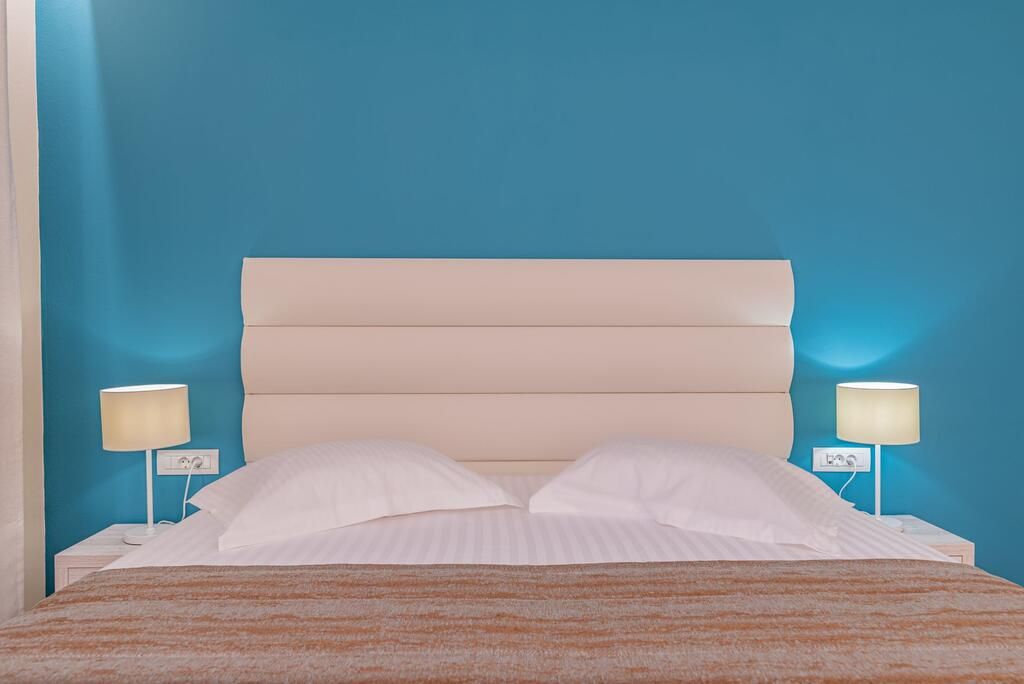 A bed with a headboard, two bedside lamps, and a striped blanket.