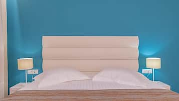 Una cama con cabecera, dos lámparas de noche y una colcha a rayas.
