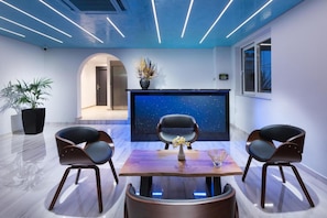 Ein modernes Interieur mit Sternenprojektion an der Wand, zwei Sessel, ein Tisch und ein Blumentopf.