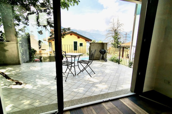 Eine Terrasse mit Fliesenboden, einem Tisch und zwei Stühlen.