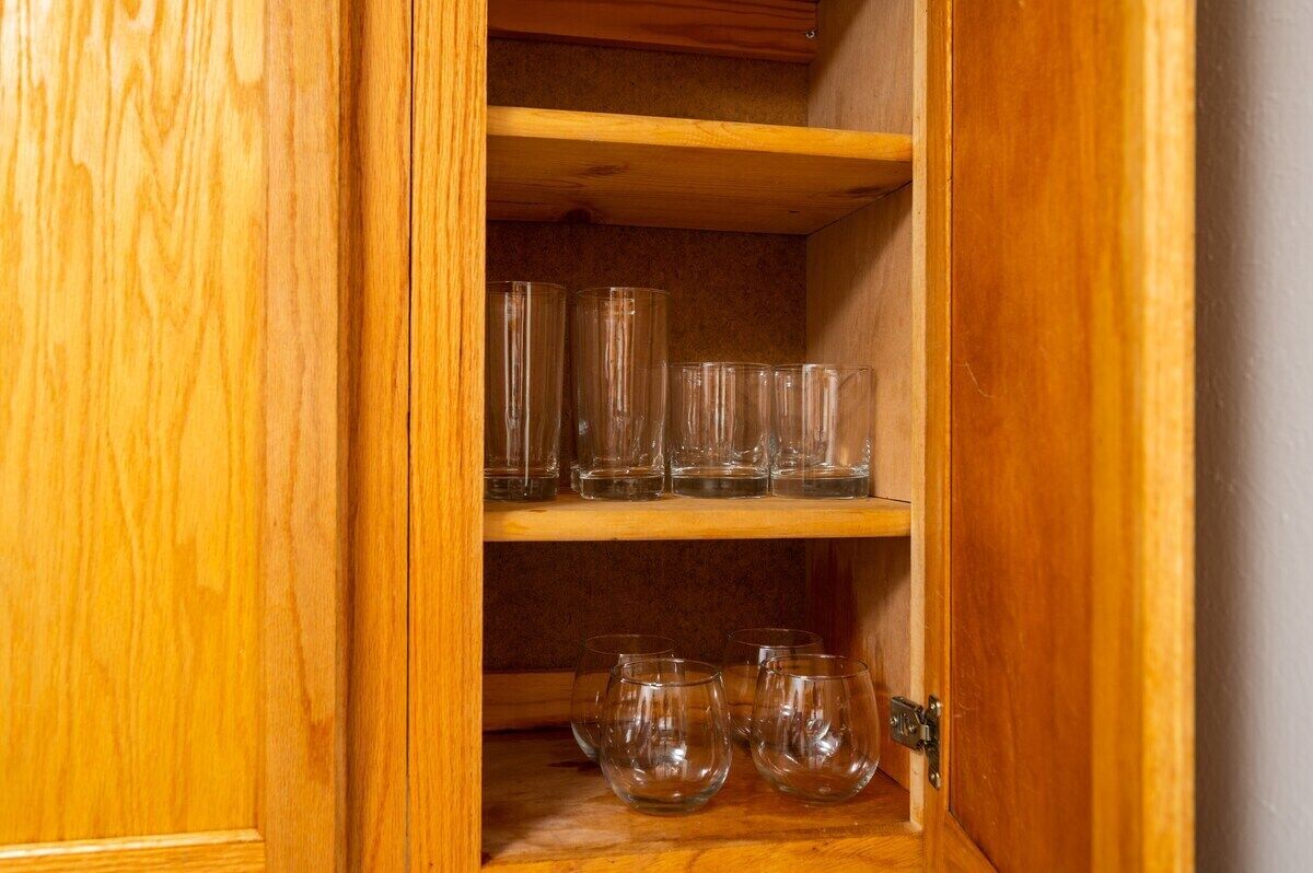 Un meuble en bois doté d’étagères où sont rangés des verres transparents.