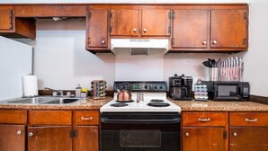 Une cuisine dotée de meubles de rangement en bois, d’une cuisinière, d’un four à micro-ondes et de divers ustensiles de cuisine.