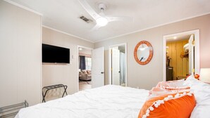 Une chambre d’hôtel équipée d’un lit, d’une télévision, d’un miroir et d’un ventilateur de plafond.